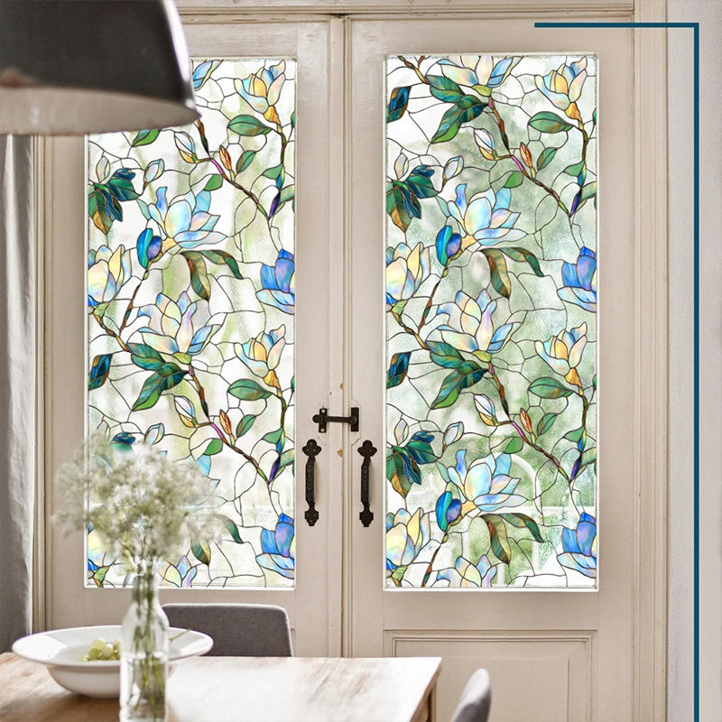 A close-up view of a floral stained glass window film applied to a white door, featuring blue and green leaves and flowers.
