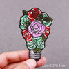 An embroidered floral bouquet featuring red and pink roses on a dark green background.