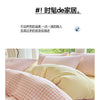 Close-up of a pink and white checkered duvet cover set with two pillows on a bed.
