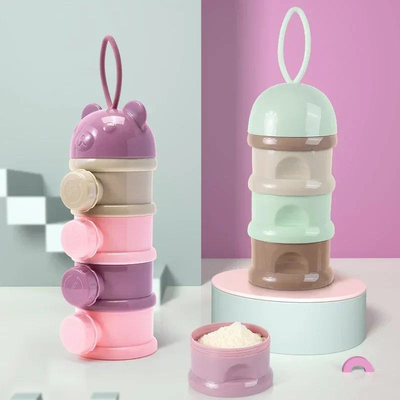 A stack of three pastel pink and green bear-shaped baby food storage containers with loop lids