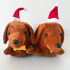 A pair of brown dachshund plush slippers with red and white Santa hats.