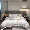 Luxuriöses Schlafzimmer mit Bett und weißer Bettwäsche in neutralen Tönen, beleuchtet durch modernes Licht.