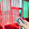 A hand holds a remote control for USB LED curtain lights with various modes, illuminating sheer pink curtains.