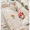 A beige sofa covered with Christmas tree patterned fabric and decorative pillows on a light rug.