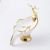 A white ceramic soap dish shaped like a leaf with a gold-colored drain rack and deer antlers.