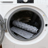 A close-up view of a gray non-slip suction cup bath mat with massage nodes inside a white washing machine drum.