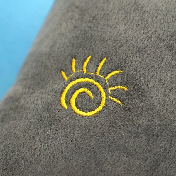 A close-up of a gray car seat featuring a yellow sun design embroidered on the fabric.