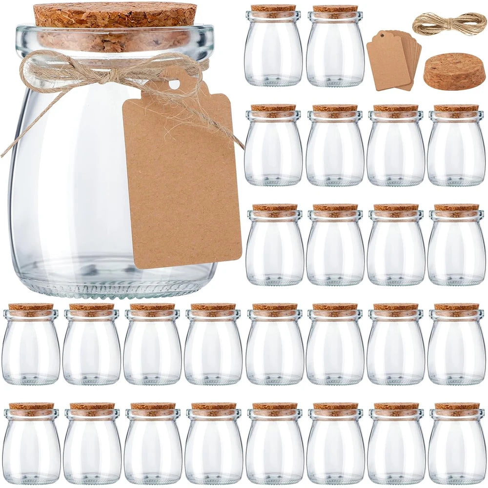 A collection of mini glass favor jars with cork lids in various sizes and natural twine packaging.