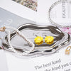 A silver cloud-shaped tray holds pearl necklaces and yellow floral earrings.