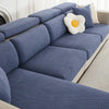 A navy blue jacquard elastic sofa slipcover with a textured fabric and a cream flower cushion.