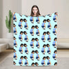 A playful cartoon throw blanket featuring stylized figures in blue and white on a light blue background.