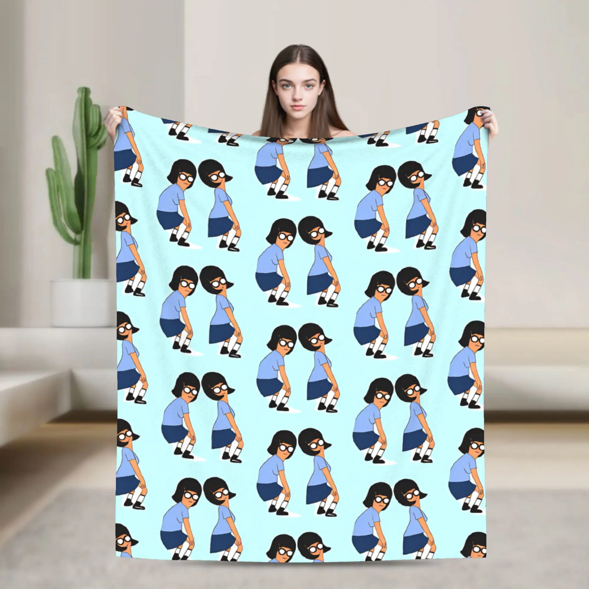 A playful cartoon throw blanket featuring stylized figures in blue and white on a light blue background.