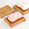 Natural bamboo soap dish holding a white bar of soap and a pink bar of soap