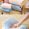 A stack of various colored cloud velvet bath towels, including pink, light blue, and white, are displayed on a wooden rack.