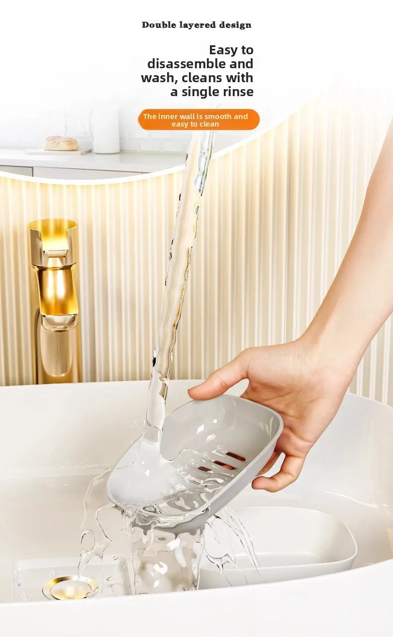 A hand is pouring water into a white double-layered draining soap dish in a bathroom sink.