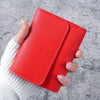 A hand holds a red slim triple-fold PU leather wallet against a gray background.