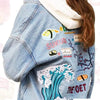 A denim shirt featuring embroidered cartoon iron-on patches with a pink theme.
