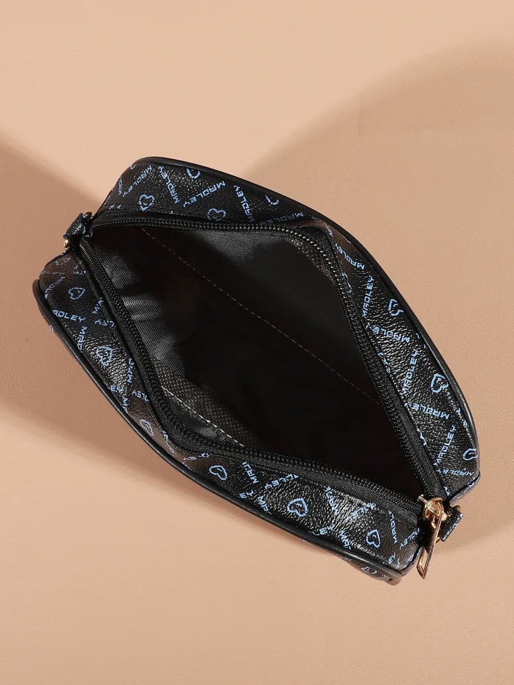 A black compact crossbody bag with a zippered opening and a patterned fabric detail is shown against a beige background.