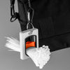 A white cable tie organizer with an orange component is clipped to a black bag, showing a bundle of white ties.