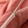 Close-up of a peach colored pinch pleated duvet cover with a gold zipper detail.