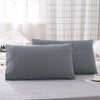 A set of two solid gray microfiber pillowcases resting on a light gray bed sheet.