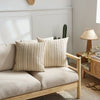 A set of two beige woven linen pillow covers on a light wood bed frame with a natural rug.