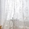 Sheer white lace curtains with floral embroidery draped in a romantic style