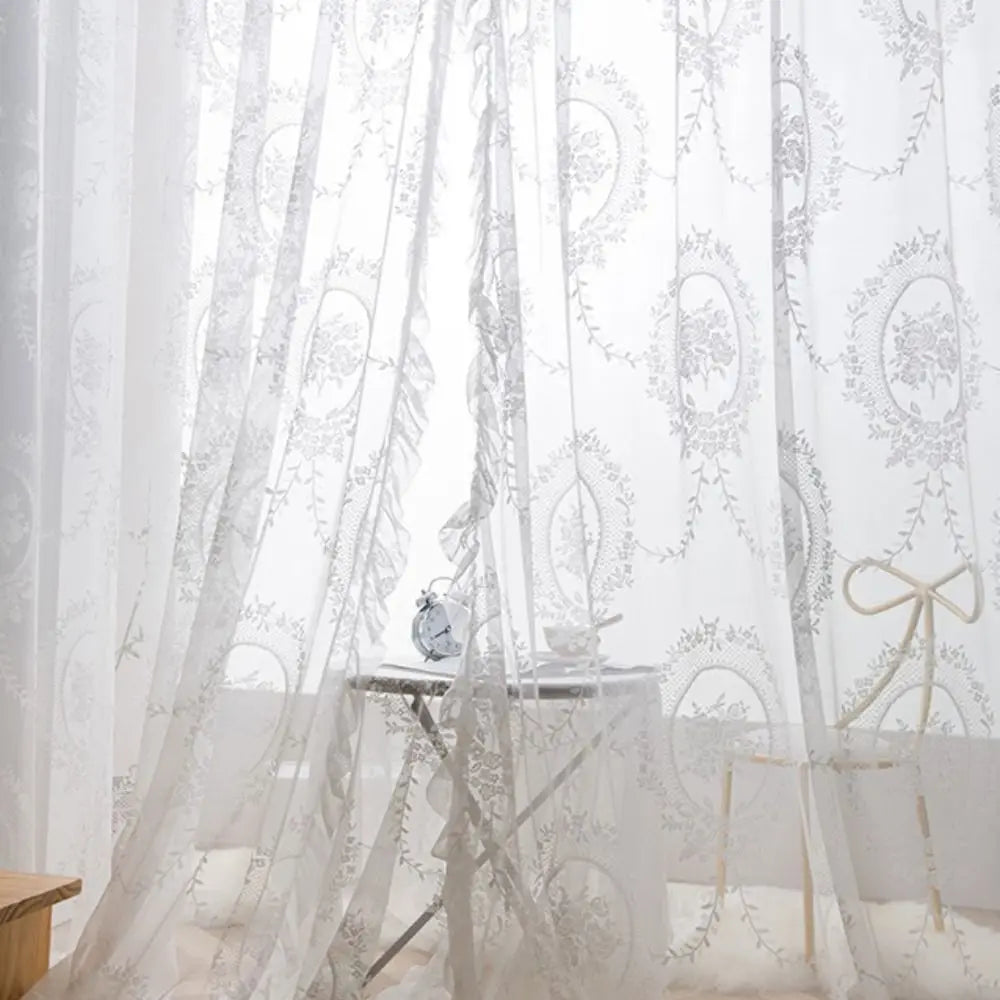 Sheer white lace curtains with floral embroidery draped in a romantic style