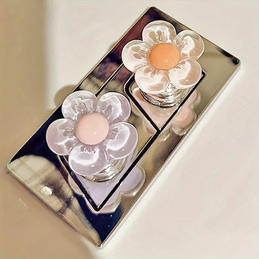 A silver tray holds two glass containers with pink and white floral toilet flush handles.