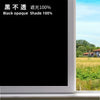 A close-up view of a window with black opaque shade film applied, showing a bright outdoor landscape.