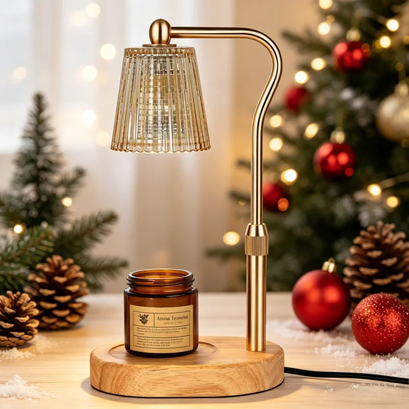 A brass electric candle warmer lamp with a textured glass shade sits on a wooden surface near a decorated Christmas tree.