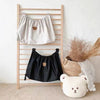 A wooden rack displaying two bear-themed fabric organizers, one white and one black.