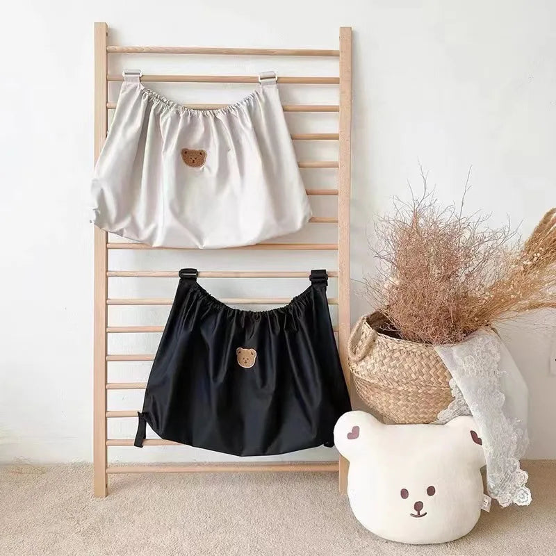 A wooden rack displaying two bear-themed fabric organizers, one white and one black.