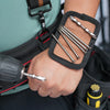 A hand is using a magnetic tool to attach or detach a black wrist strap with a phone holder and suspenders.