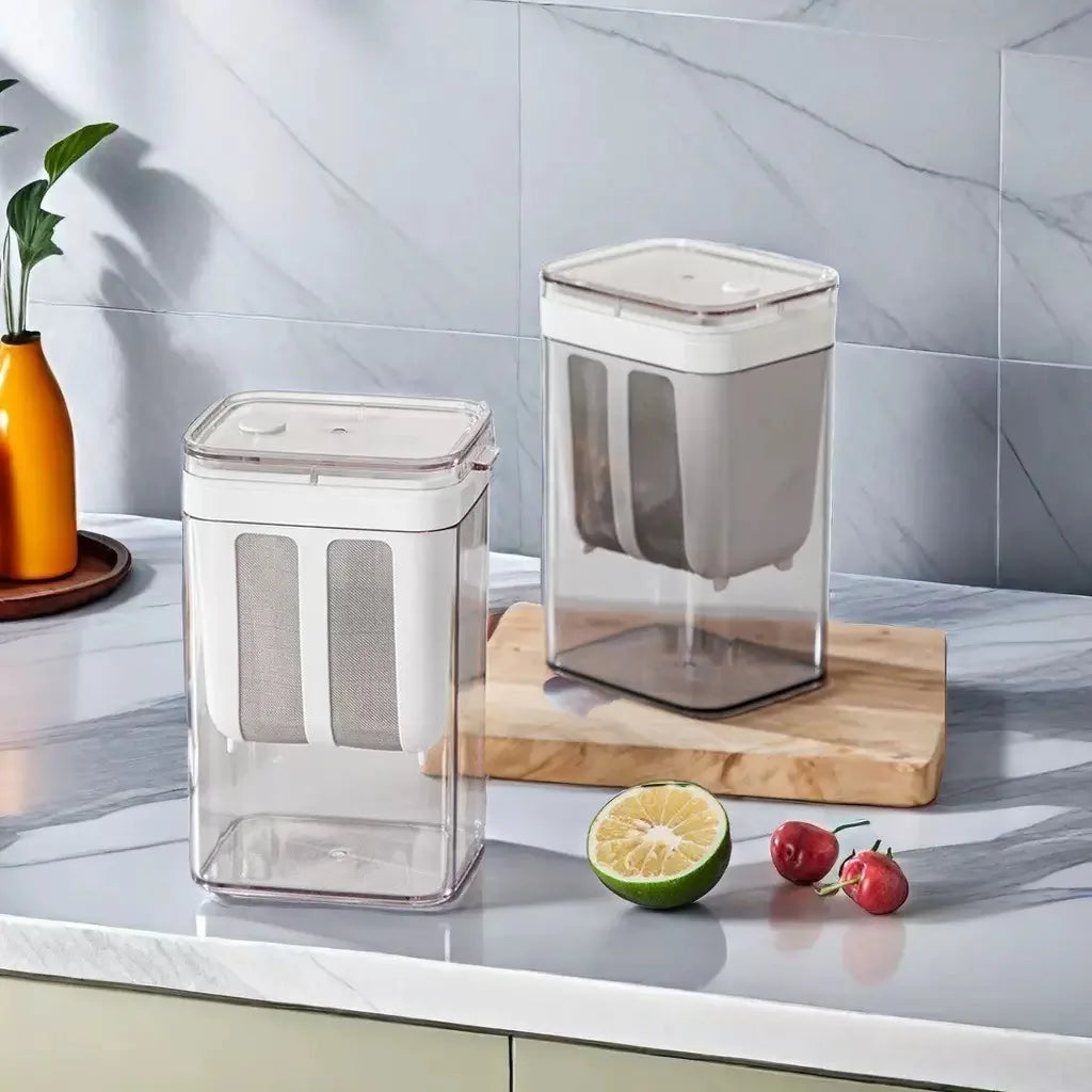 A clear stainless steel yogurt strainer with a fine mesh filter sits on a wooden cutting board next to a lime.