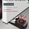 A black portable door stopper alarm device with a wedge design is shown on a wooden surface.