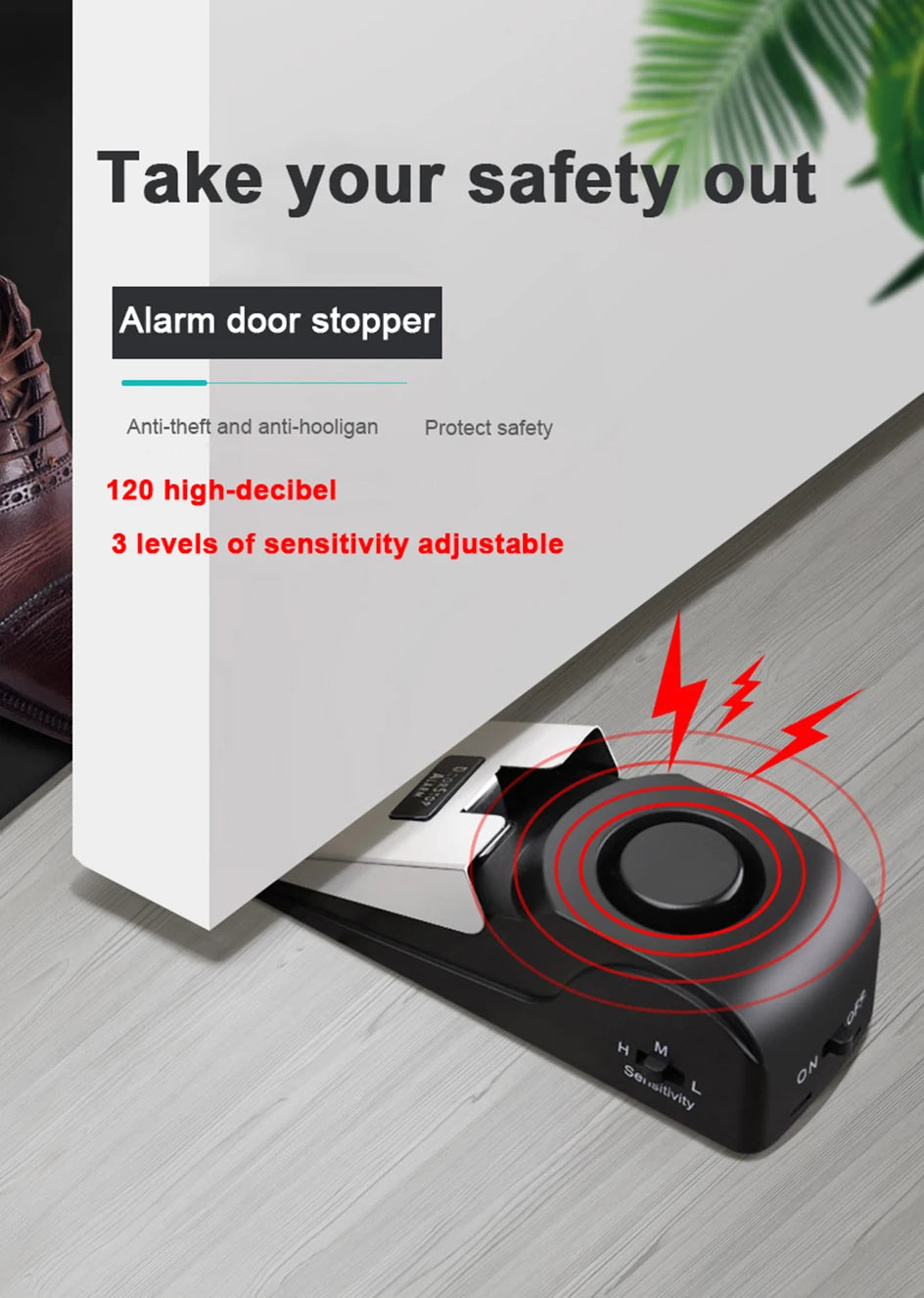 A black portable door stopper alarm device with a wedge design is shown on a wooden surface.