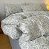 A set of soft printed duvet covers and pillowcases in gray and white floral patterns on a bed.