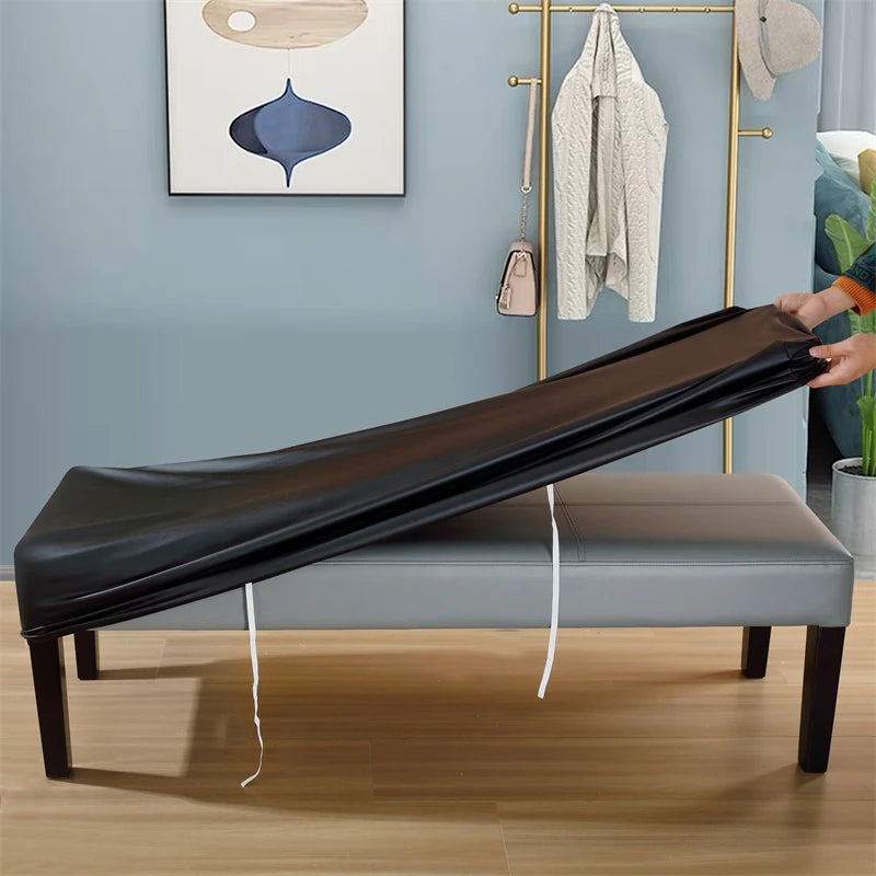 A black waterproof stretch bench cover is shown on a wooden bench, with a gold-toned rack and a light gray wall in the backgr