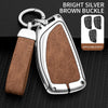 A silver key case with a brown buckle and leather strap is shown against a black background.