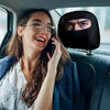 A woman wearing glasses is talking on a phone while sitting in a car, with a black eye print headrest cover visible.