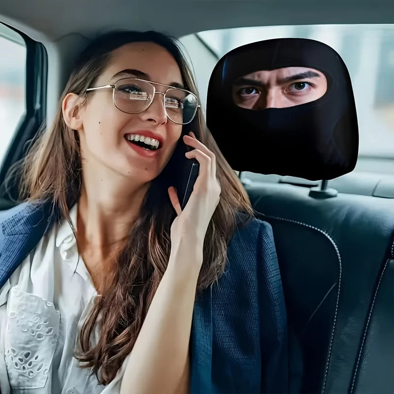 A woman wearing glasses is talking on a phone while sitting in a car, with a black eye print headrest cover visible.
