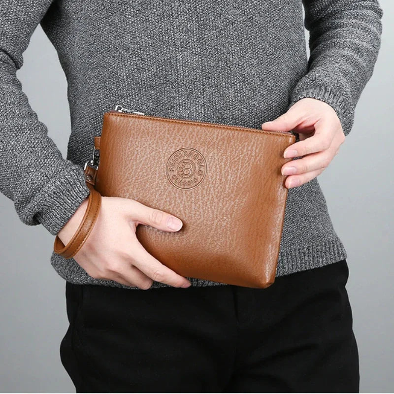 Eine Person hält eine elegante braune Leder-Geldbörse für Herren gegen einen grauen Pullover und schwarze Hose.