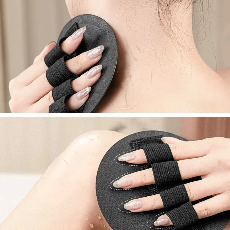 A hand wearing a black silicone exfoliating body scrub glove on the wrist, showing the textured grip and design.