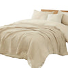 Beige, große 6-lagige Baumwollgaze-Decke über einem Bett mit weißen Kissen.