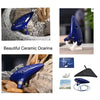 A beautiful blue ceramic ocarina with a mouthpiece, music book, and storage bag displayed on rocks.