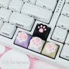 A close-up view of silicone keycaps featuring kawaii cat paw and pink heart designs for MX switches.
