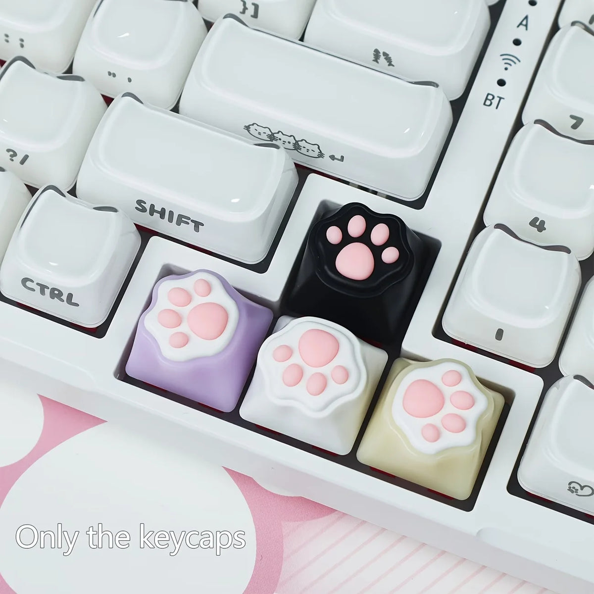 A close-up view of silicone keycaps featuring kawaii cat paw and pink heart designs for MX switches.
