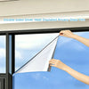 Hands applying double-sided silver heat-insulated privacy glass film to a window pane.