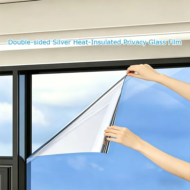 Hands applying double-sided silver heat-insulated privacy glass film to a window pane.
